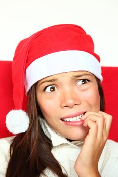 Christmas woman with santa hat nervous biting nails. Beautiful mixed asian / caucasian model. 