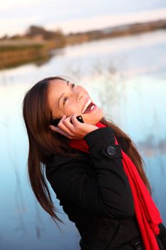 Laughing woman on the phone. Casual and natural outside by the water. 
