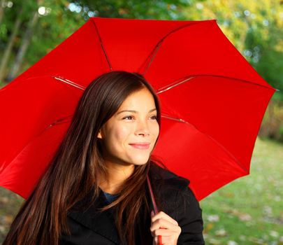 Red umbrella woman outdoors in autumn forest. Beautiful model.