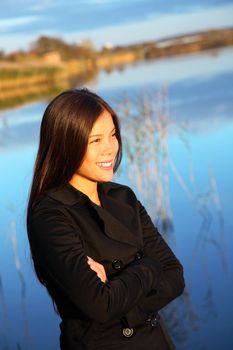 Outdoors portrait og beautiful, casual smiling mixed race caucasian / asian model in warm evening light by the water.