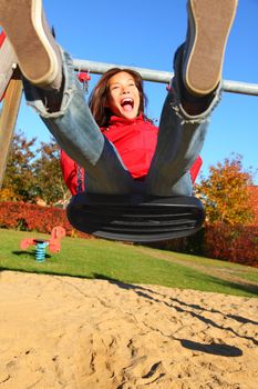 Swing. Happy young woman swinging on a playground.