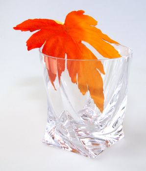 Crystal glass with maple leaf on white background