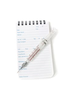 A medical notebook used my doctors and emergency services personnel and syringe needle on a white background.