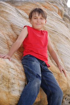 Smiling young child leaning against a tall sandstone cliff face