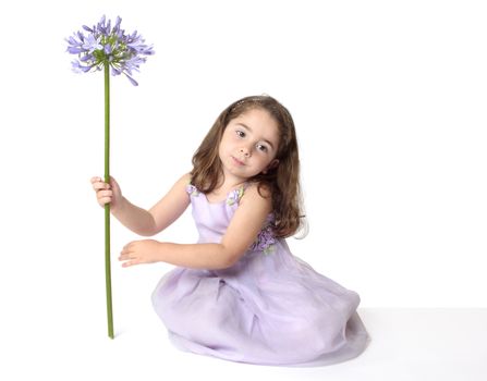 Serene girl in mauve dress holding a beautiful purple agapanthus flower.  You may swap the flower for a balloon or any other object.
