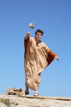 Depiction of ancient man throwing rock or stone.   concept sticks and stones, sin, condemnation, or historical reenactment.  Rock shows motion.