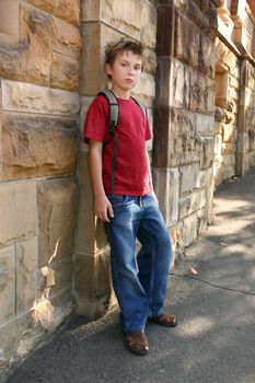 Trendy boy in denim jeans and t-shirt leaning against a standstone brick wall.
f5.6