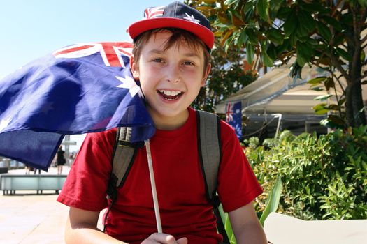 Happy patriotic young boy flying a flag on summer national day.