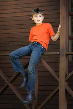 A child sits on the timber balustrade of a verandah - 400 iso