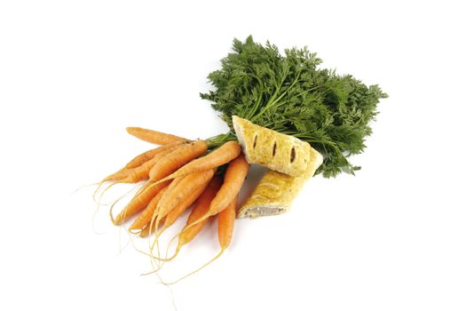 Contradiction between healthy food and junk food using bunch of carrots and sausage roll on a reflective white background 