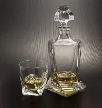 Crystal bottle and glass with light whisky on black background