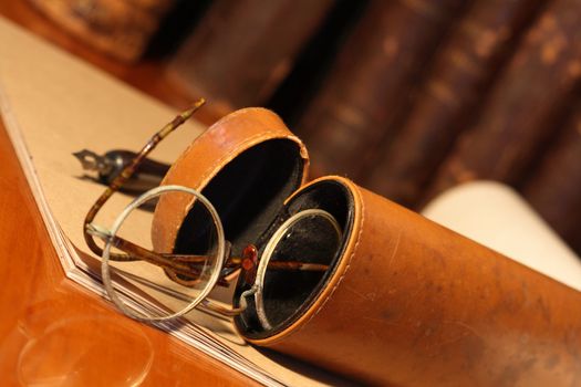 Closeup of old spectacles inside leather case on background with book