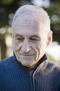 Outdoor Portrait of an Old Man in a Sweater Looking Down
