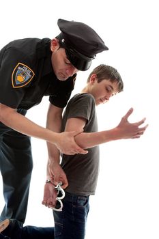 A uniformed policeman arrests and handcuffs a young teen criminal