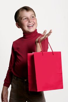 Joyous young boy with a red shopping bag