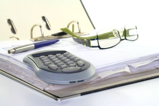open folder with filed documents, calculator, pencil and eyeglasses