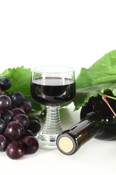 a bottle of red wine and fresh grapes on a white background