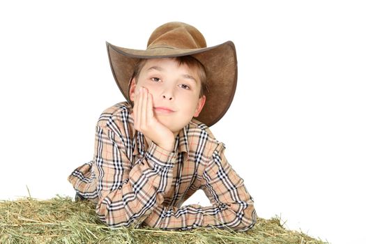 A country farm boy leaning on a bale of lucerne hay.