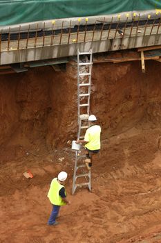 Worker climbs a ladder holding a bucket
