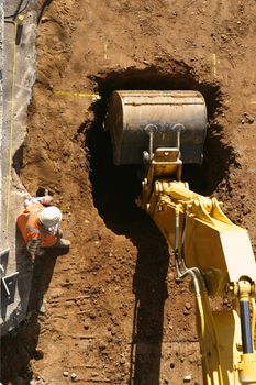 A machine digs a hole at a construction site.  
Above Perspective.
