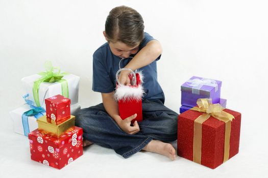 Boy opening presents on Christmas day. Gifts scattered around him.