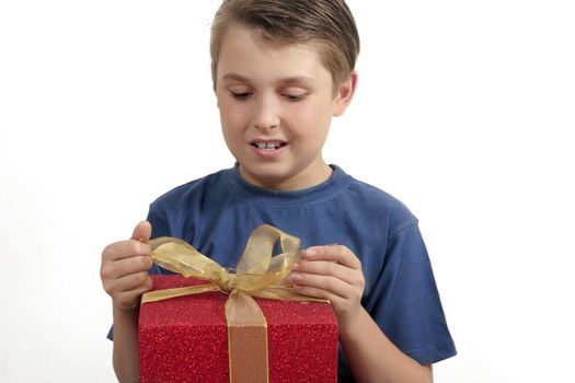 Young boy in t-shirt opening (or wrapping) a red and gold present