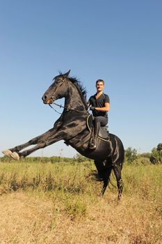 young man and his beautiful black stallion rearing up