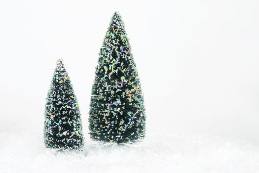 Two artificial Christmas trees on white bg.