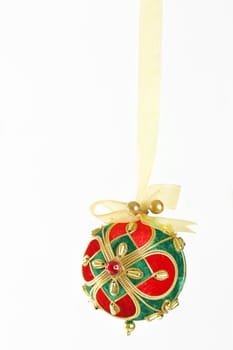 A decorative Christmas ball tied and hanging with gold organza  ribbon