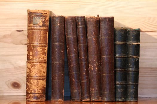 Closeup of old books standing in row on wooden background