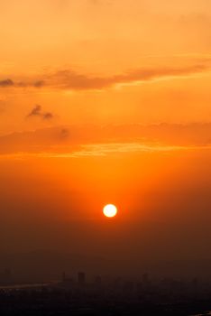 City sunset with dramatic landscape of red falling sun and silhouette of buildings.