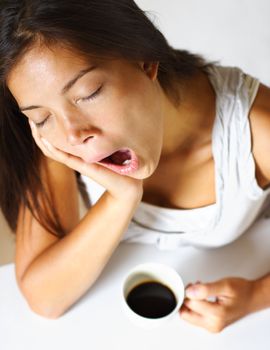young woman drinking coffee in early morning, yawning and tired.