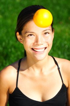 Orange and health concept -   cute picture of young woman throwing an orange in the air. T
