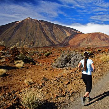 Running / jogging. Woman running on dirt road in amazing volcano landscape on Tenerife.