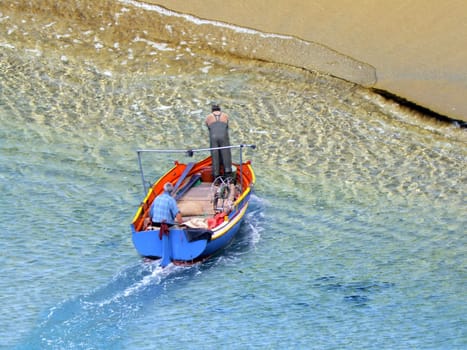 Surreal composite image of boat with fisherman next to gigantic sandy shore