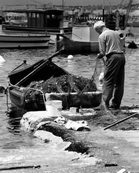 Old fisherman fixing his nets at the fishing village of Marsaxlokk in Malta