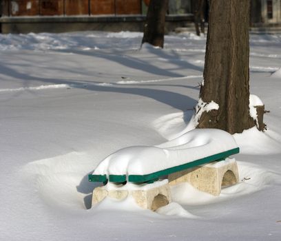 Snow covered a bench in winter