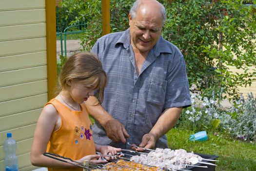 The grandfather learns the granddaughter to do a kebab