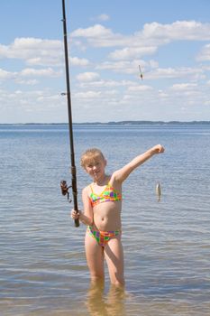 Girl holding a fish caught on a fishing line with clouds