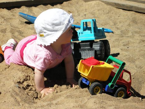 Baby in sandbox/pit discovering life.