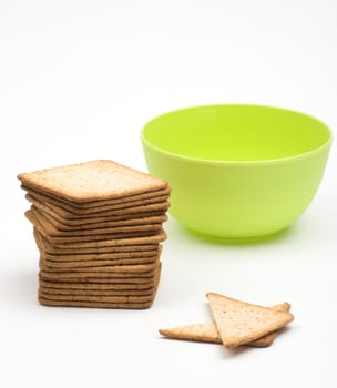 A stack of crackers  and green cup over white