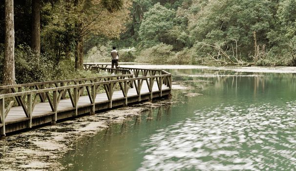 Landscape of lake with single man and forest.