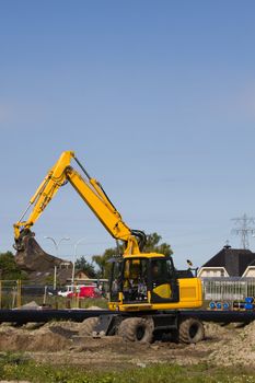 Excavator at work digging up ground for new to build houses - vertical