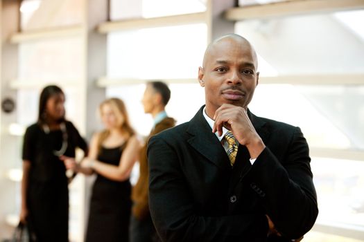 An African American business man with co-workers in the background