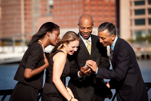 A group of business people crowded around a cell phone