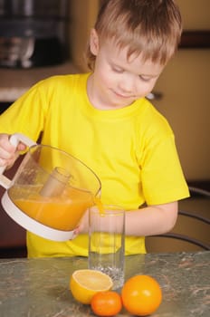 The child in a yellow vest drinks  orange juice