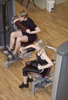 Boy and a girl using excercise machines in a health canter