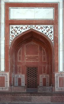 Flowerly designs on white marble against red sandstone.