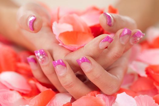 Hands with beautiful nailpolish holding rose petals