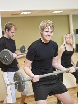 Group of people lifting weights with a young man in focus